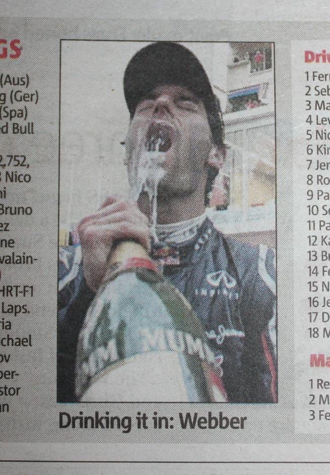 Photograph in newspaper of man spraying champagne on his face. Text reads: Drinming it in: Webber