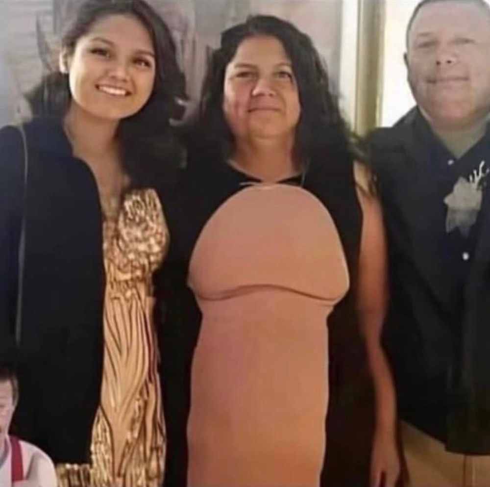 A woman poses in a black and pink dress