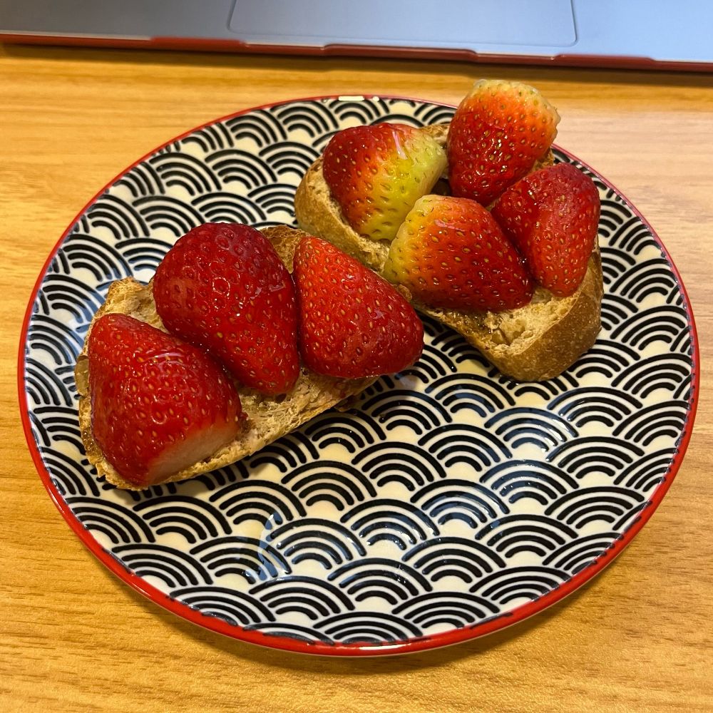 Two small pieces of toasted bread, with halved strawberries on top and drizzled with honey.