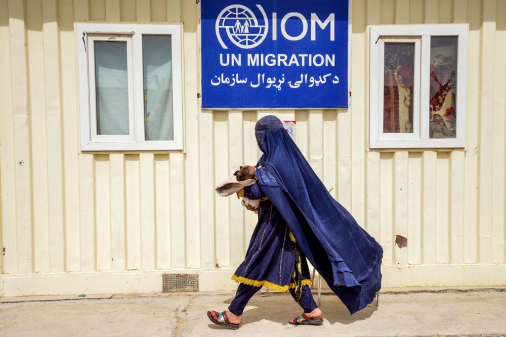 Une femme afghane avec un enfant devant le bureau des Nations Unies pour l'émigration. Elle porte une Burqa bleue et porte l'enfant dans ses bras. 

©AFP - Sanaullah SEIAM