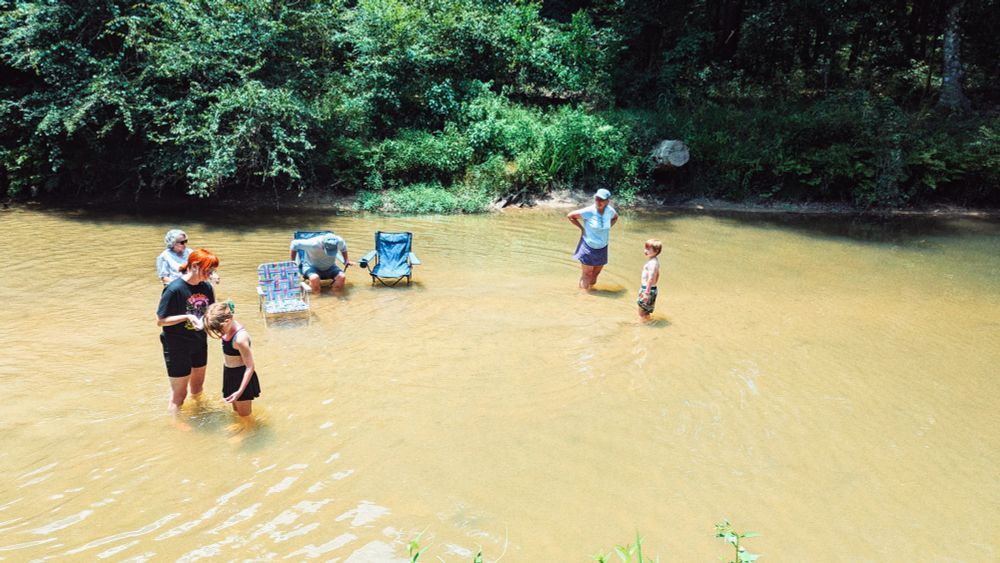 Creek with folding chairs and people 