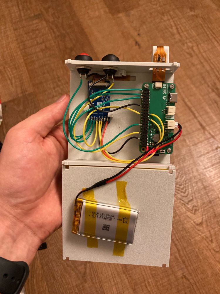 The device consists of a circuit board with wires connecting to other parts. Including a battery, ribbon cable to camera, wires to the SPI eink driver board. Red yellow black and green wires. Looks a little sketchy to bring through the airport 