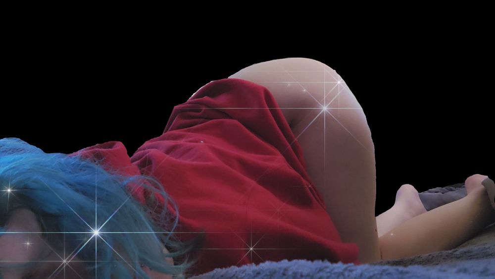 Vampiricc, leaning over on her tummy, her ass in the air. She is wearing a red champion hoodie and nothing else. She has electric blue hair, she's laying on a plush blue blanket. The background is black with white sparkles in the photo. 