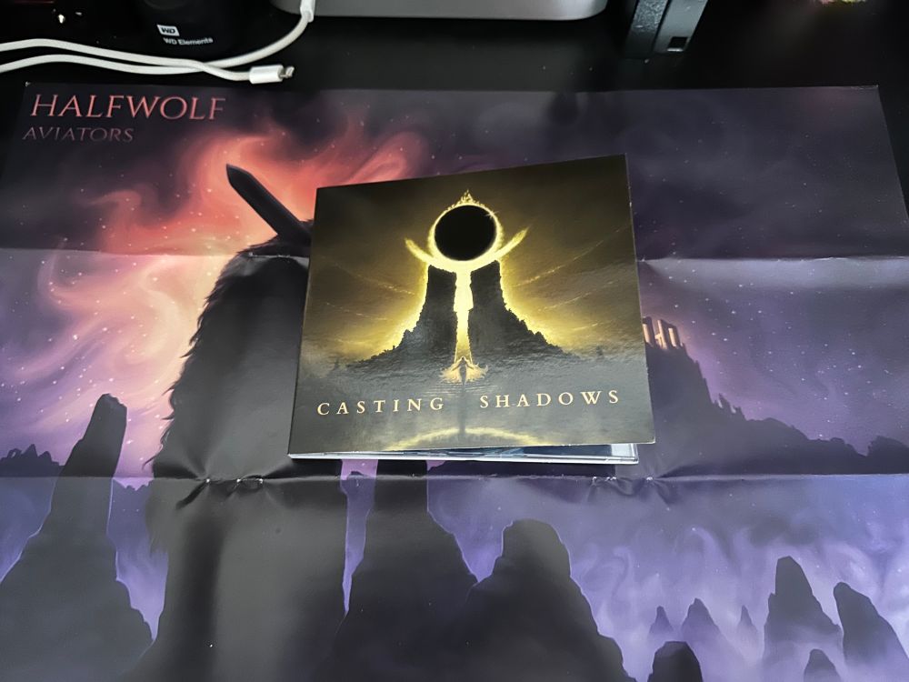 A CD case with the name Casting Shadows in the foreground and two large pillars with an eclipsed sun in the background. 