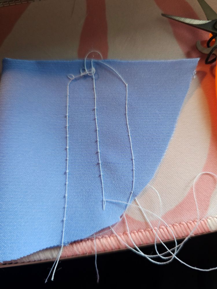 Very poorly tensioned lines of stitching on a scrap of blue satin