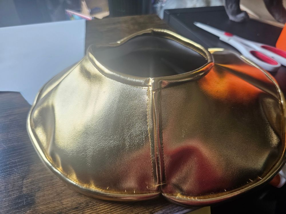The back of a gold pleather wide necklace showing a slit in the back so it can slip over the head