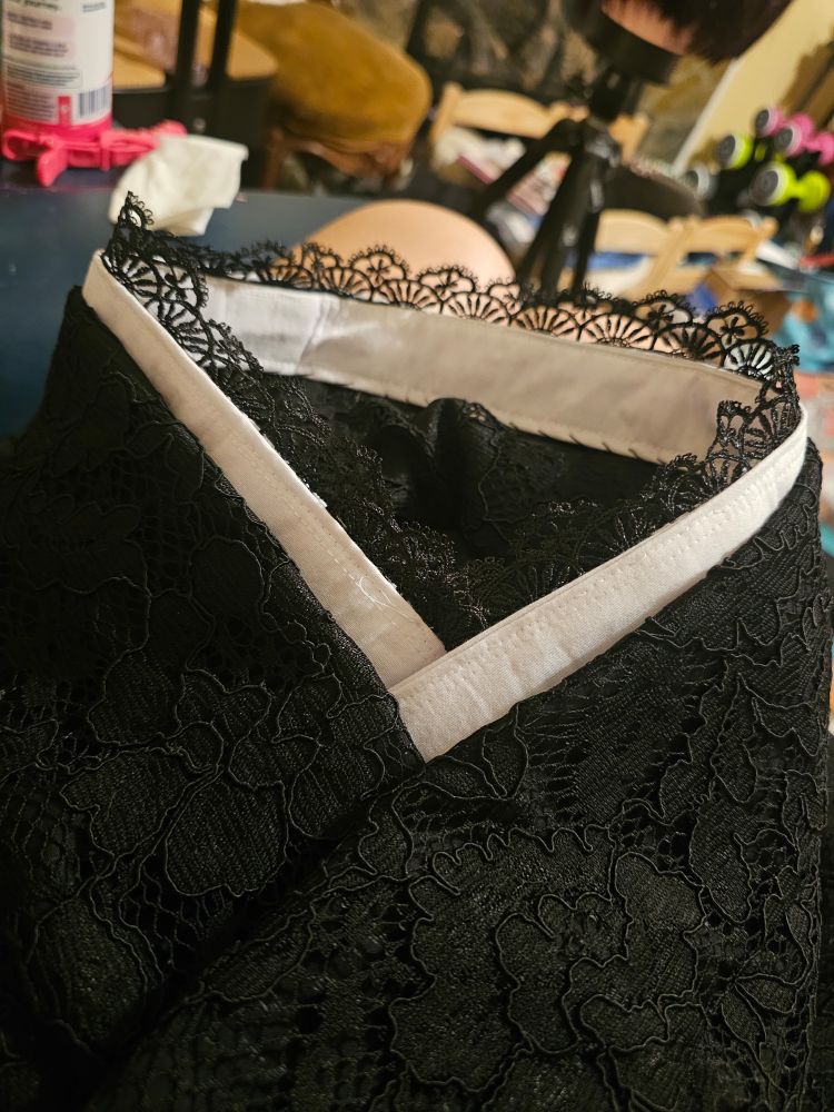 The collar of a black kimono with lace overlay with a white false collar with black lace on the top edge attached to it