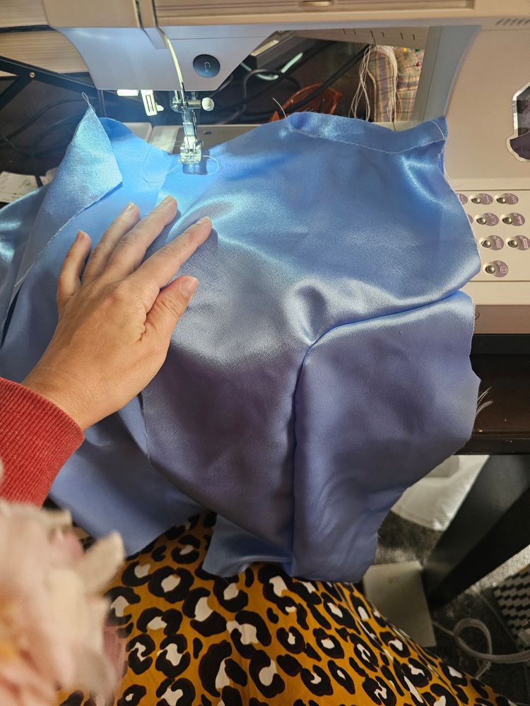 A blue bodice on a sewing machine. The bodice is sewn with a panel backwards.