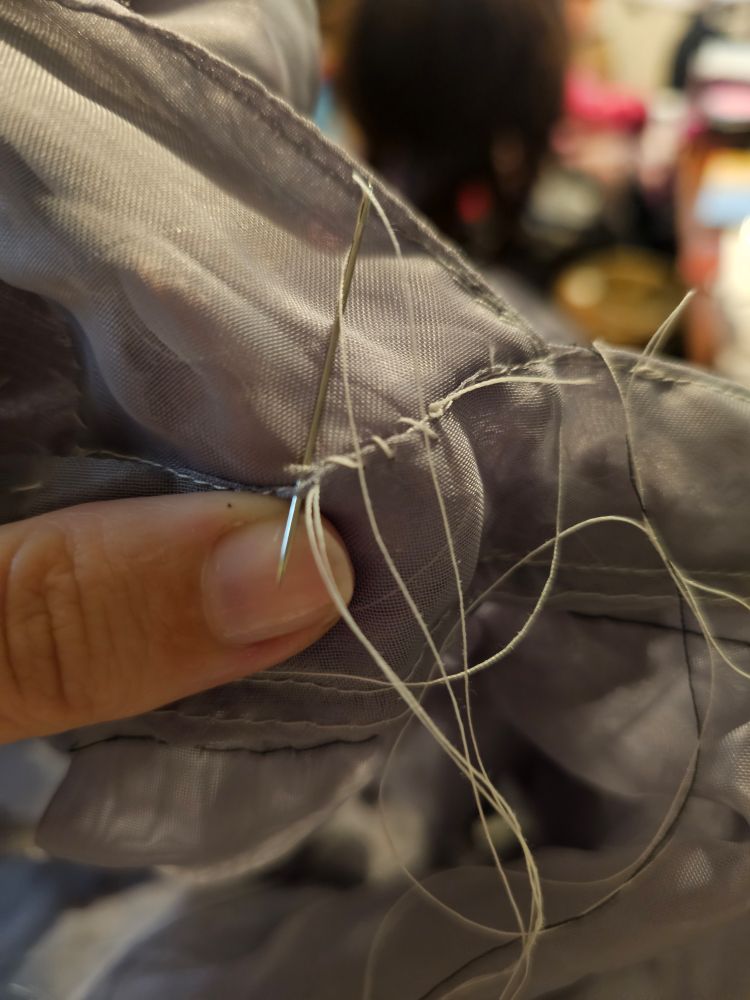 Someone holding a sewing needle in a way that when it goes through the fabric, it skids across the corner of the left thumbnail. If you zoom in, you can see scrape marks from this on the nail