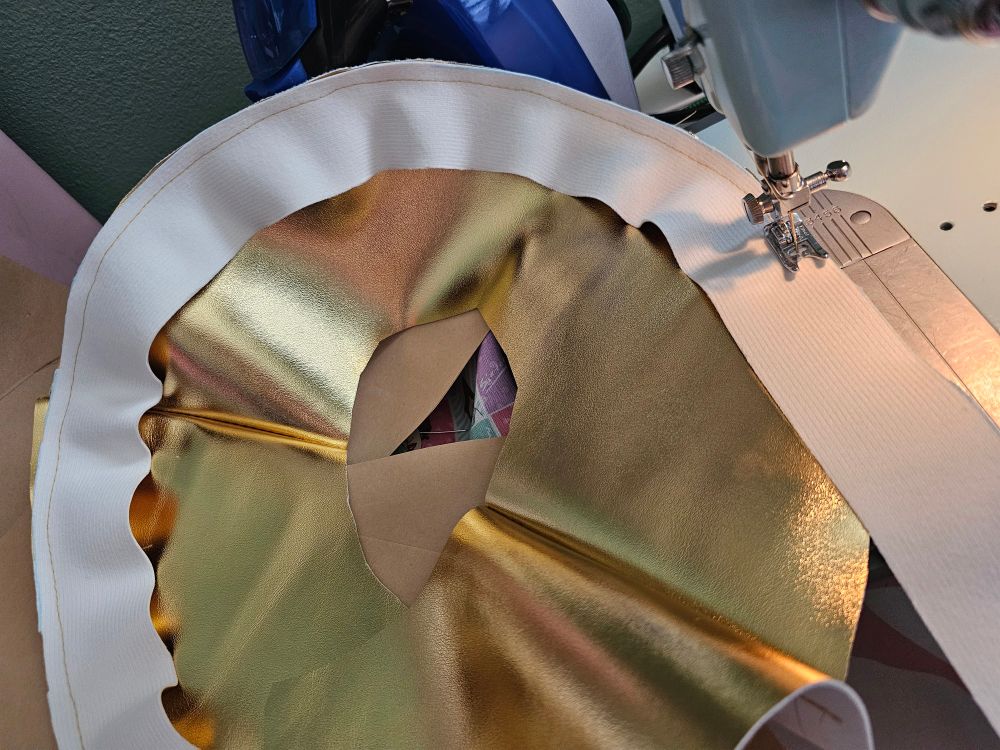 A gold pleather circle with a strip being sewn around the edge