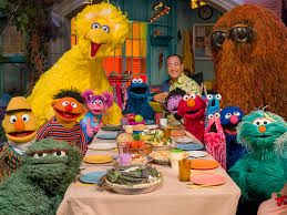 Beloved Sesame Street characters at a dinner table, including Oscar the Grouch, Bert and Ernie, Big Bird, and Elmo