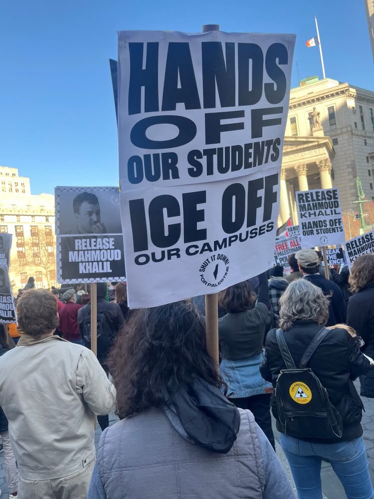 A protester holding a sign that says Hands off our students, ICE off of our campus. 