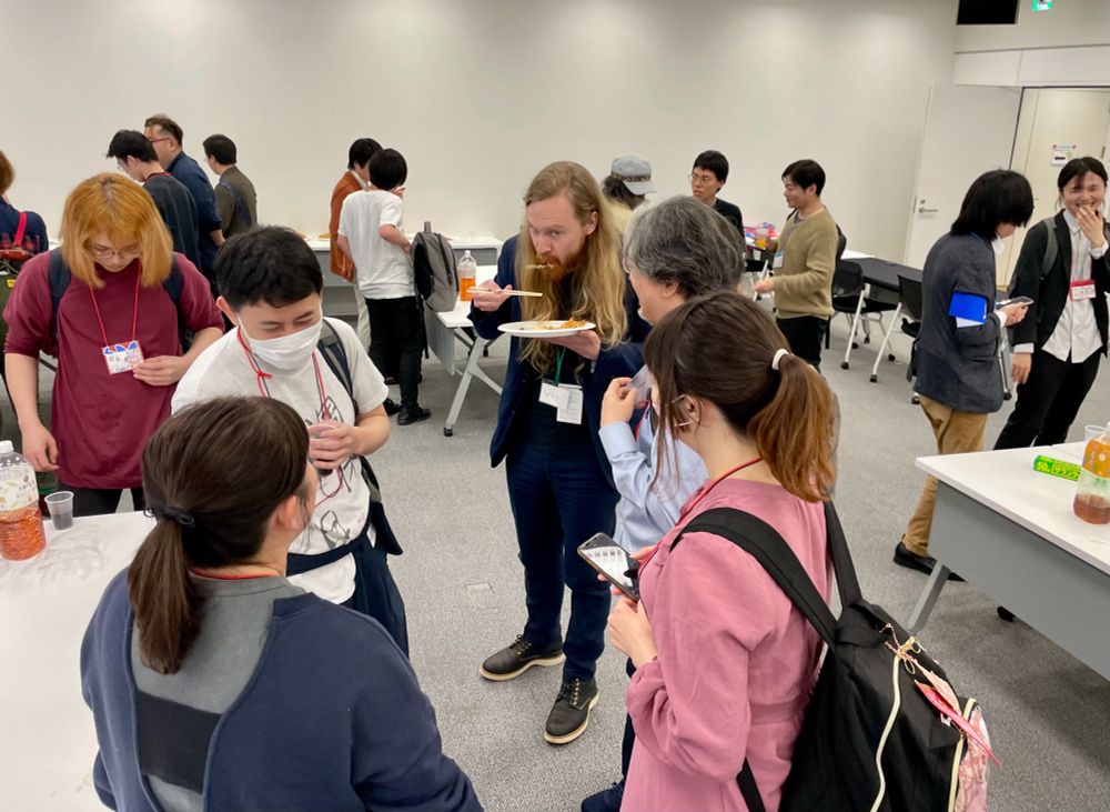 懇親会で参加者と料理や交流を楽しむWhyさん（中央）