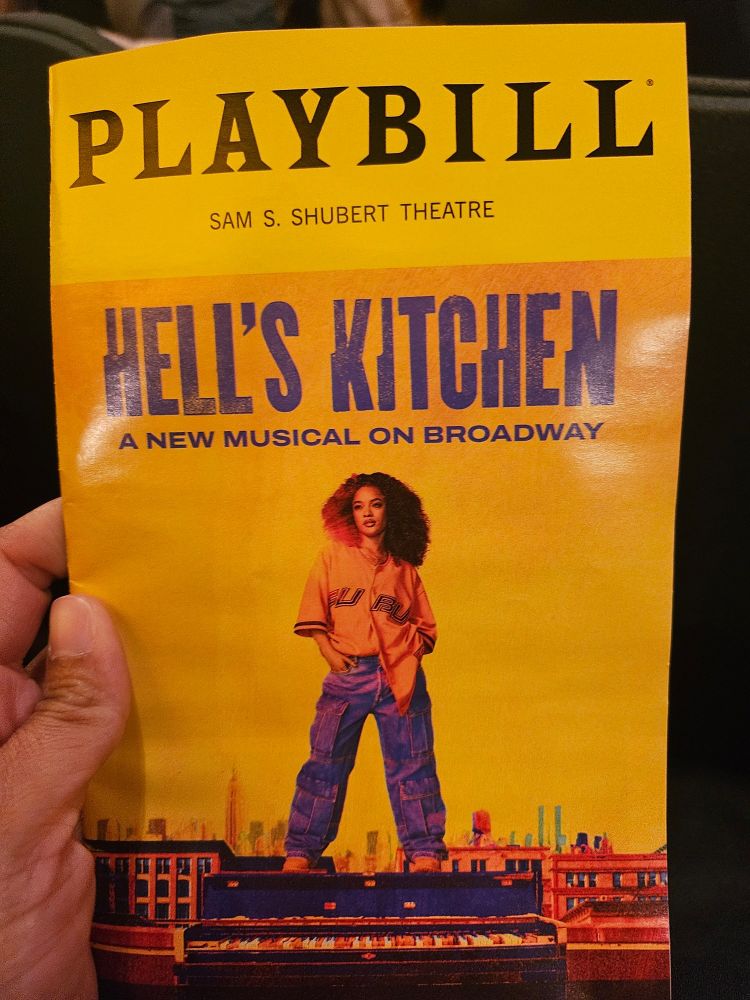 The playbill for Hell's Kitchen with a girl in 90s gear (yellow baseball tee and bag jeans) standing on a rooftop. 