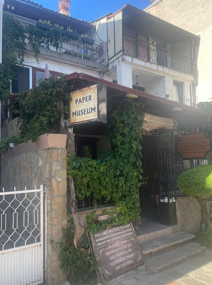 A slightly ramshackle assemblage of low-rise buildings. At the front a creeper-covered entrance way, with a sign reading “Paper Museum”