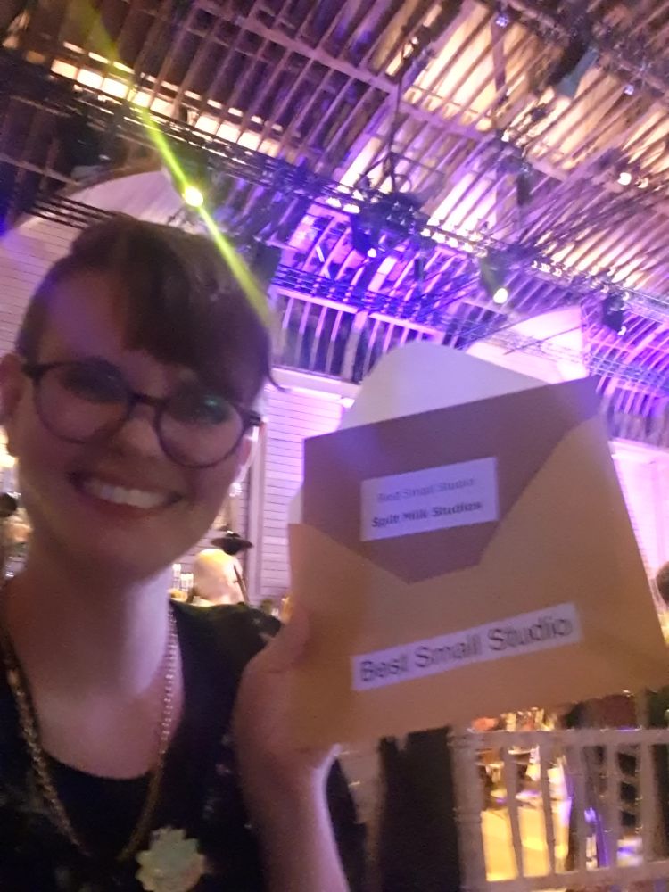 selfie holding an envelope showing Spilt Milk Studio as the winner of the best small studio award
