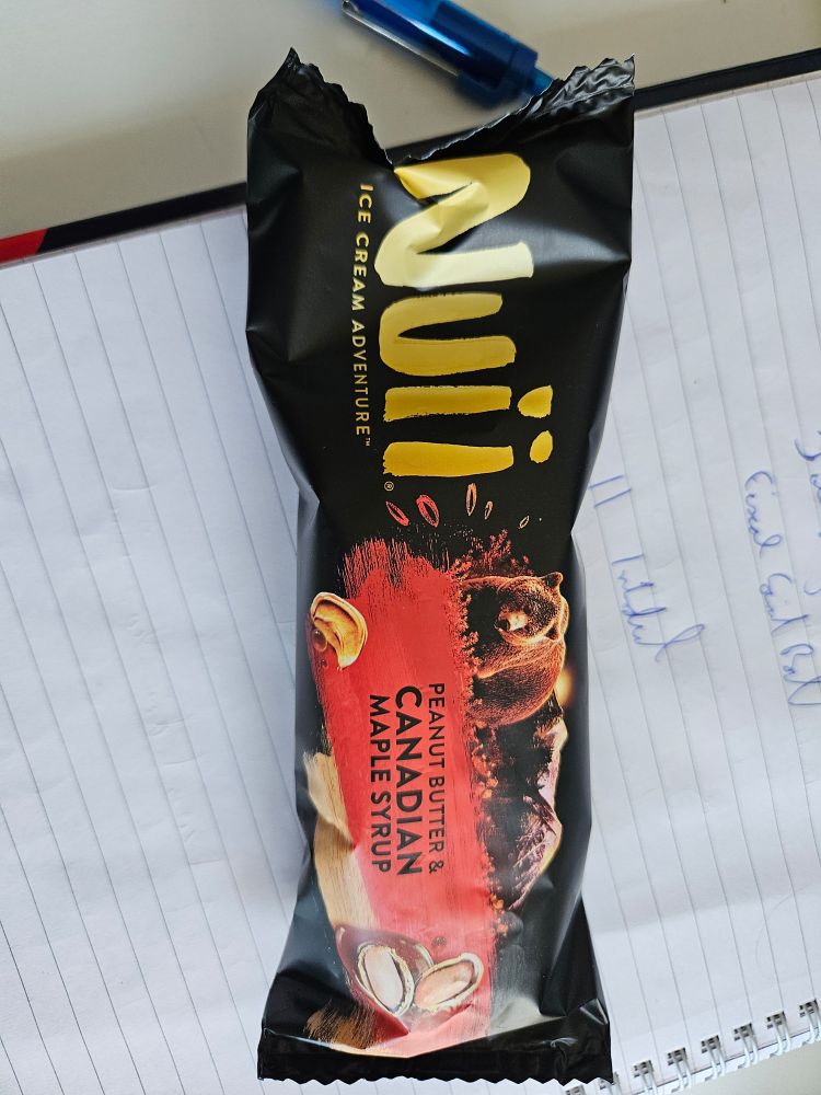 Picture of a still wrapped nuii peanut butter and maple syrup chocolate ice cream, sitting on a file block