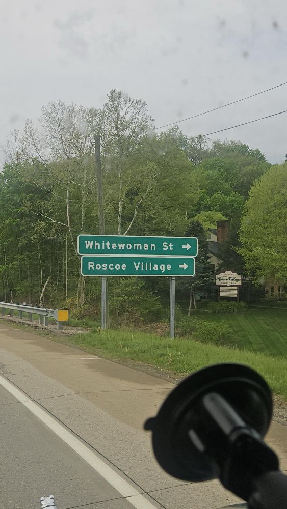 A road sign that says whitewoman Street and below it says Roscoe Village