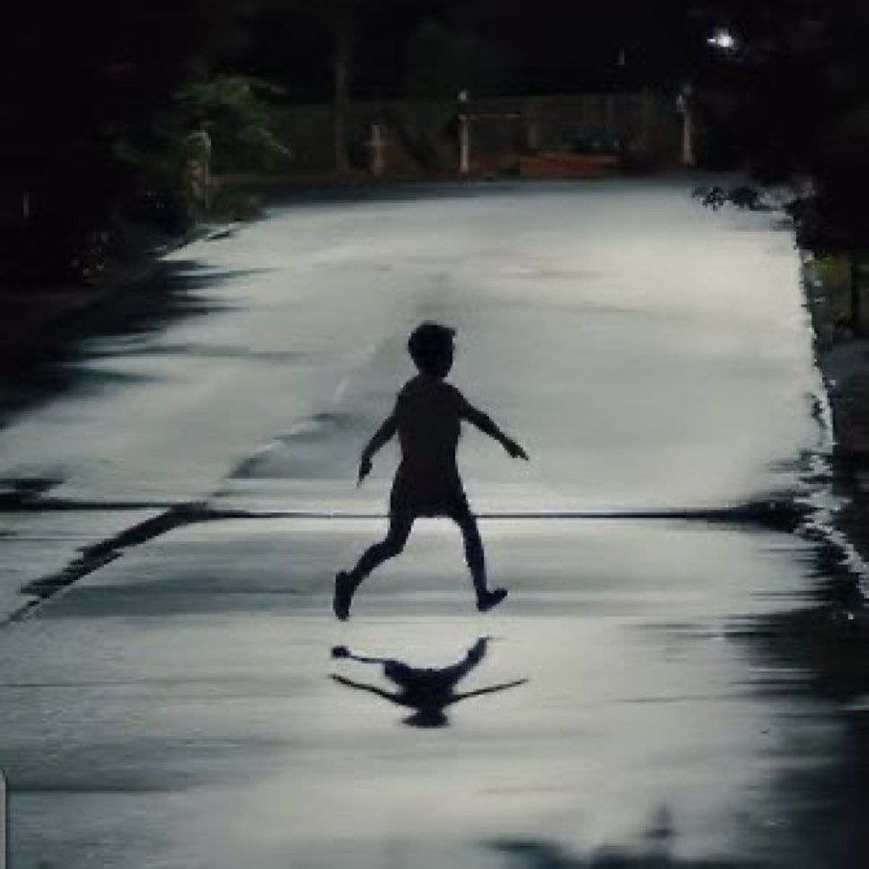 A photo from the movie Weapons that shows a little kid with his arms sticking out at his sides running on a street night time 