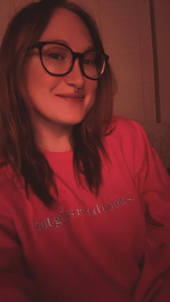 A selfie of Deviwestside wearing a hot pink sweatshirt that says “hot girls read books.”