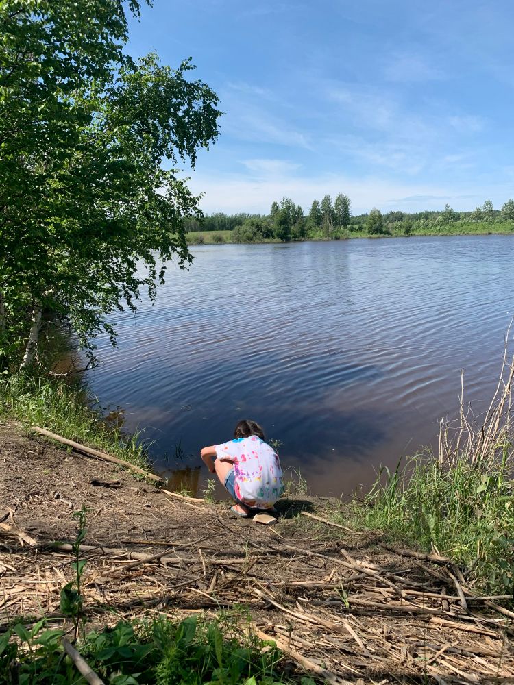 girl, looking into a pond as she crouches down
