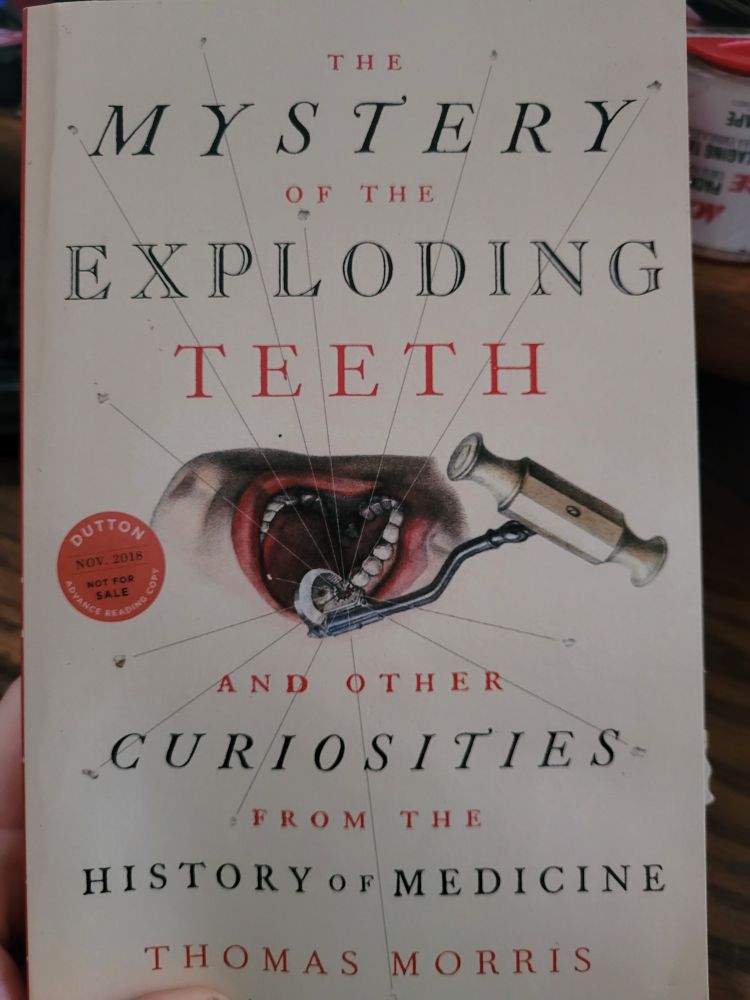 A picture of a cover of a book. It's a white-cream color with an older illustration of a painful looking tool being inserted into someone's mouth. There's a red circle labeled: Dutton. Advance Reading Copy. Nov 2018. Not for sale. 

The title is: The Mystery of the Exploding Teeth and Other Curiosities from the History of Medicine, by Thomas Morris

There's a piece of paper sticking out near the bottom right of the book, a series of little bumpy bits.  