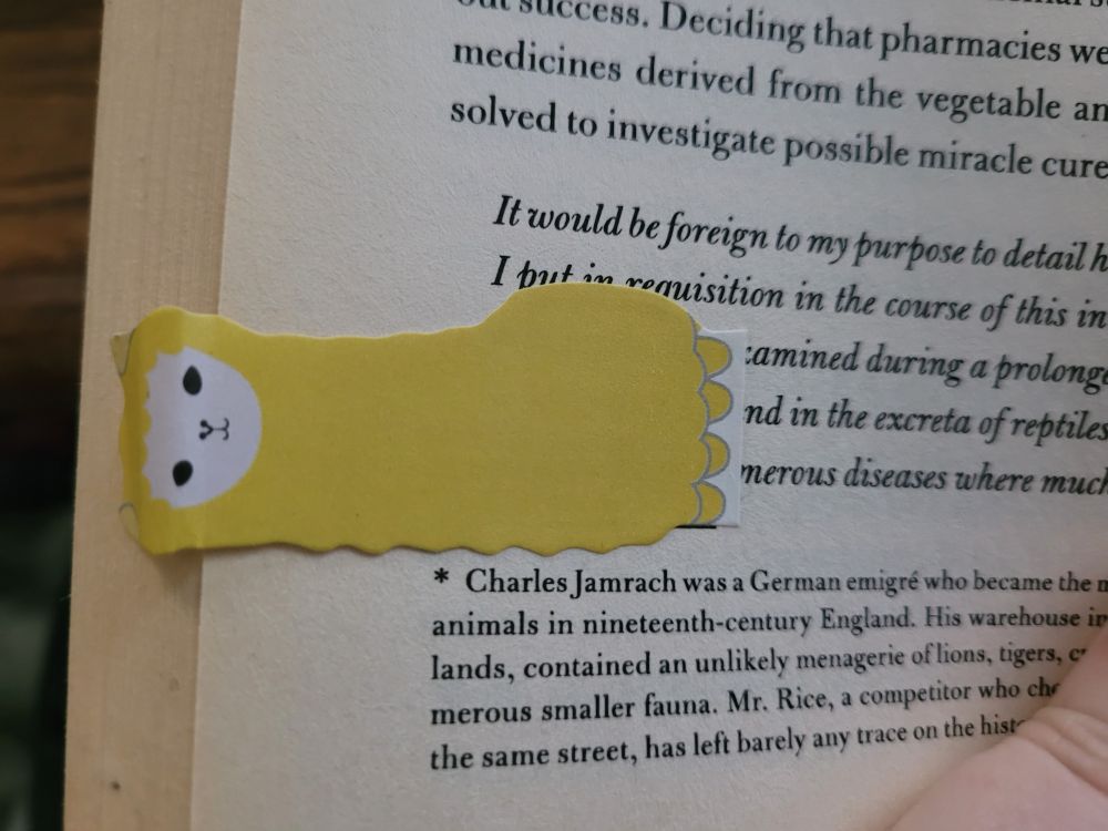 A close up pic of the bookmark used: a yellow llama sticky note with a smug resting bitch face look staring at the viewer. There are random bits of text from the book, but no real complete sentences are shown. 

One of the llama's feet is pointing to a chunk of text: "...and in the excreta of reptiles..."