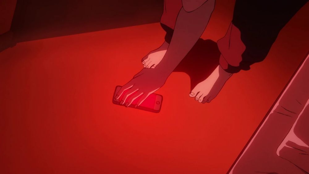A hand reaches down to pick up a phone, the screen is blood red, casting a red glow onto the hand and the surrounding floor and carpet. 