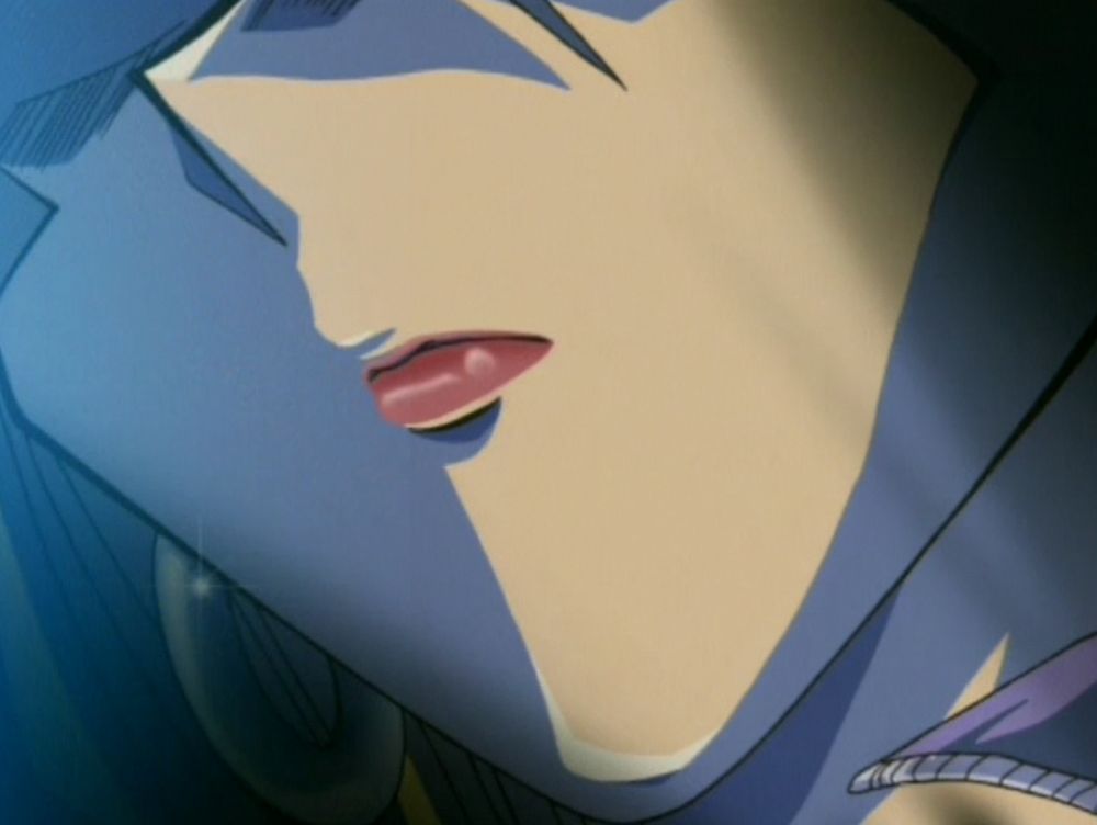 a closeup of Mai's mouth/jaw, her hooped earrings and the collar of her vest is visible in frame