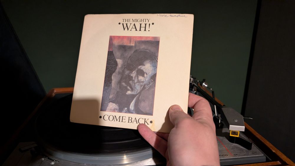 A photograph of The Mighty Wah's "Come Back" held above a very old turntable. I'm doing it. Oh you know I am doing it.