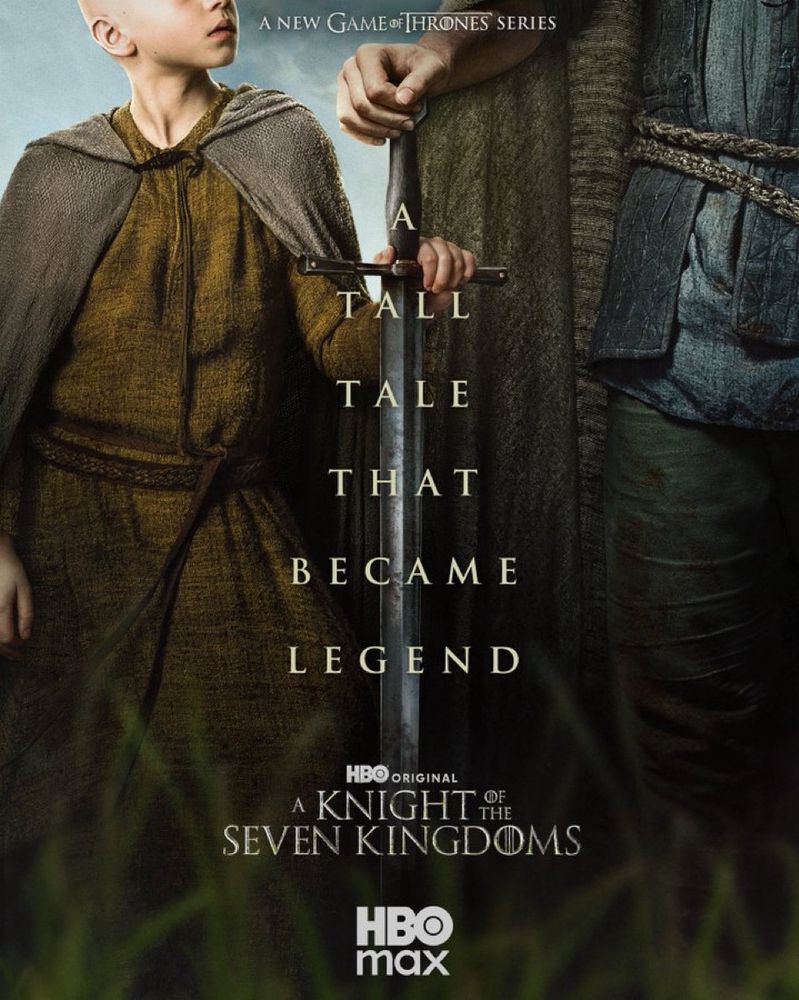 Photo of a young white boy in home spun clothing with his hand on the hilt of a long sword with its point on the ground between him and a *very* tall young white man also wearing home spun clothing. The poster is cut off so you can’t see their faces. The text reads “the tall tale that became legend.”