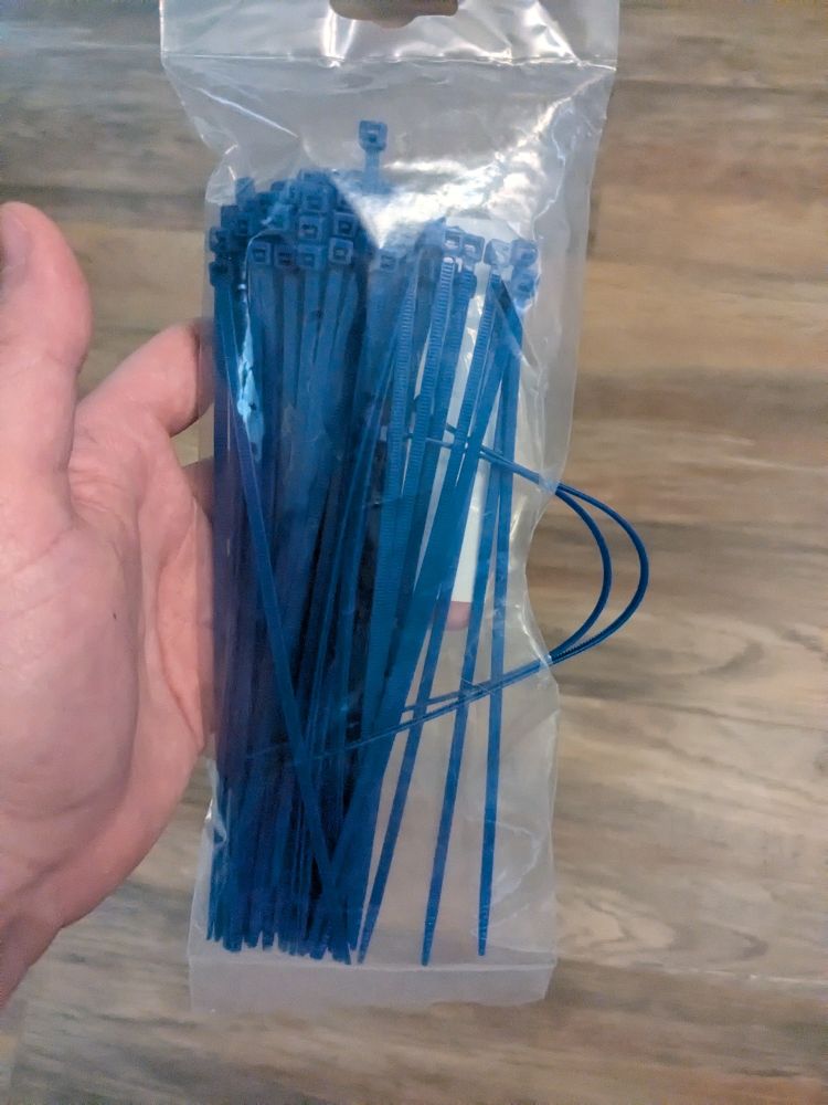 Bag of zip ties with a notch cut out of the side so you can grab them but they can't fall out. Usually a one or two inch notch in the centre of the side of the bag works fine