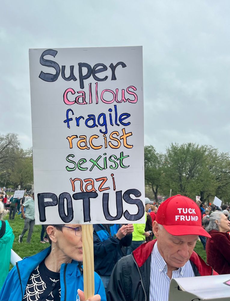 Protestor holds a sign at Hands off rally that reads, “super callous fragile racist sexist nazi POTUS”