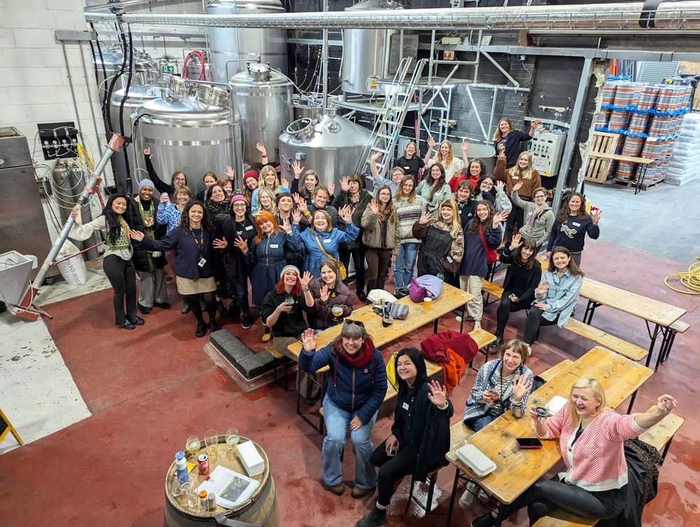 Big group of amazing women in a brewery waving at the camera for International Women's Day!