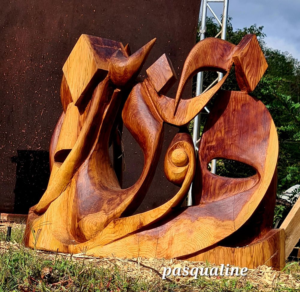 Une trace calligraphiée sculptée dans le bois. Le sculpteur travaille avec des tronçonneuses.