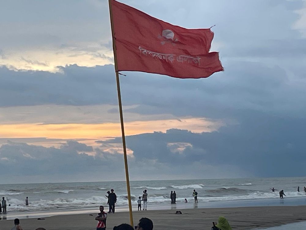 A red safety flag flying on a beach in Cox's Bazar at sunset