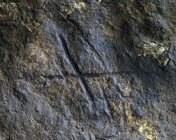 Neanderthal cave art from Gorham's Cave, Gibraltar: Pictured is a dark stone cave wall, into which has been dug a hashed or crossed mark made of intersecting straight lines.