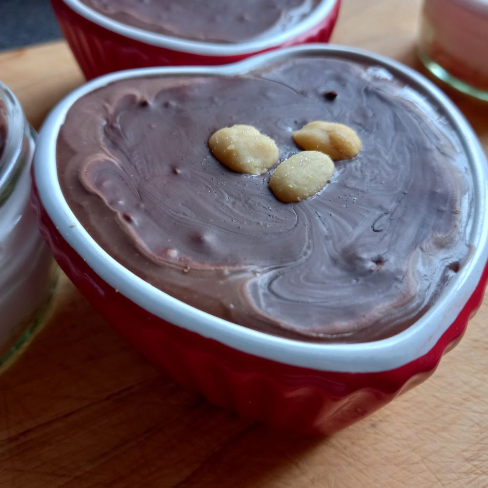 Close up of chocolate cheesecake topped with peanuts in a heart shaped ramekin