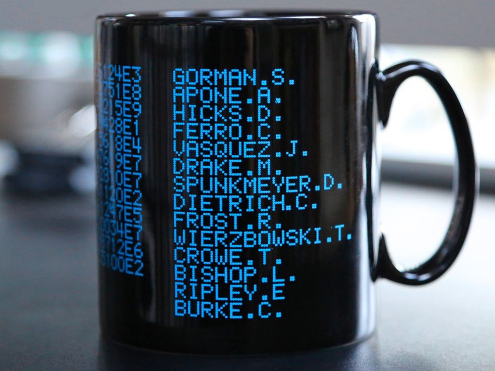 A black mug with the crew of the Sulaco crew from Aliens rendered in blue dot matrix text. Pvt Hudson is missing 