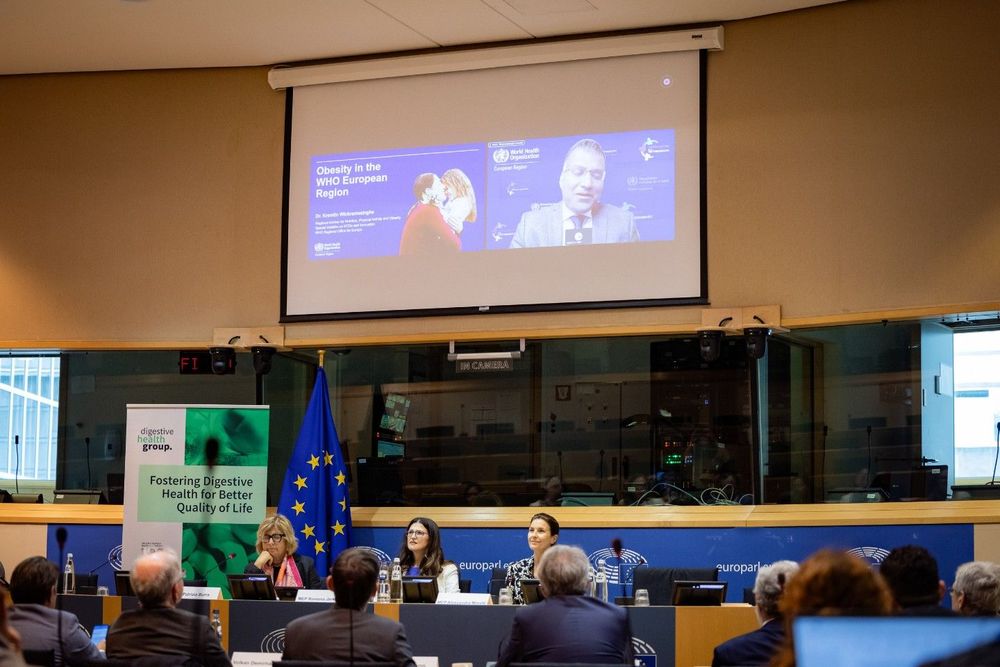 a group of people sitting at a table in front of a screen