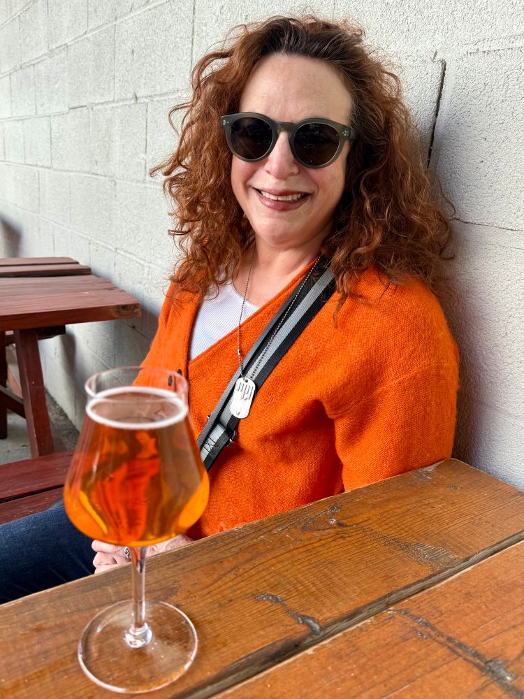 Lori wearing orange the same color as her beer. 