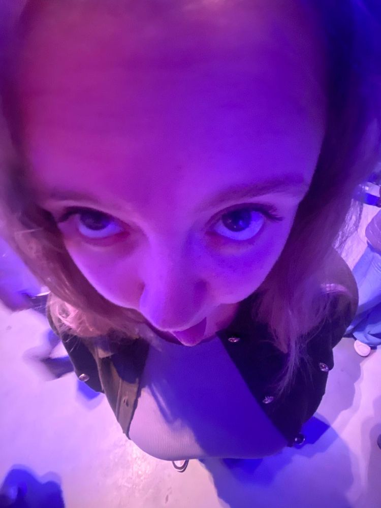 A purple tinted picture of me from a high angle, Im looking up to the camera and sticking my tongue out, also my massive boobies