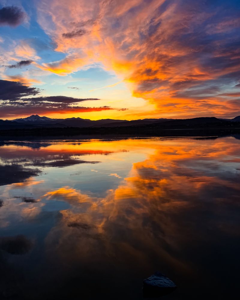 A breathtaking sunset over water, fiery hues of orange, yellow, red, and violet radiating across the sky, reflecting passion and strength, the last light burning brilliantly before nightfall, mountains silhouetted on the horizon, a moment of power and transformation, nature’s raw beauty, the sky alive with color, deep emotions stirred by the fading light, resilience in the face of darkness, energy, warmth, inspiration, reflection, the beauty of endings and new beginnings, fire in the sky, the essence of a fierce heart, nature, outdoors, personal power, strength, sunset, sky, colorful, photography, photo, scenic, landscape, adventure, freedom, spirit, empowerment, healing, energy, vitality, breathtaking, artistic, vision, mindfulness, connection, wild, expansive, limitless, heart, passion, purpose, outdoors, Colorado, reflection, compassion, fierce, fiery 
By Eric Meleney @redcranehealth