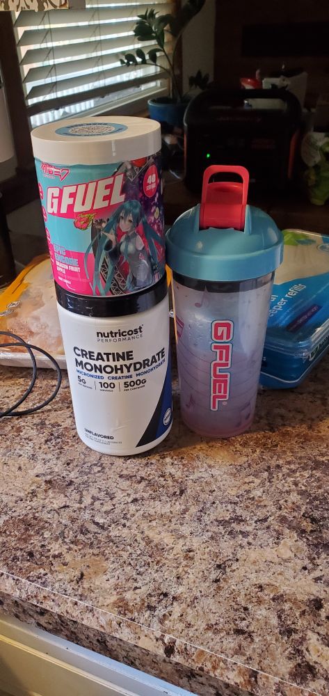 Gfuel Miku cup with jar of creatine powder and dragonfruit apple gfuel. 