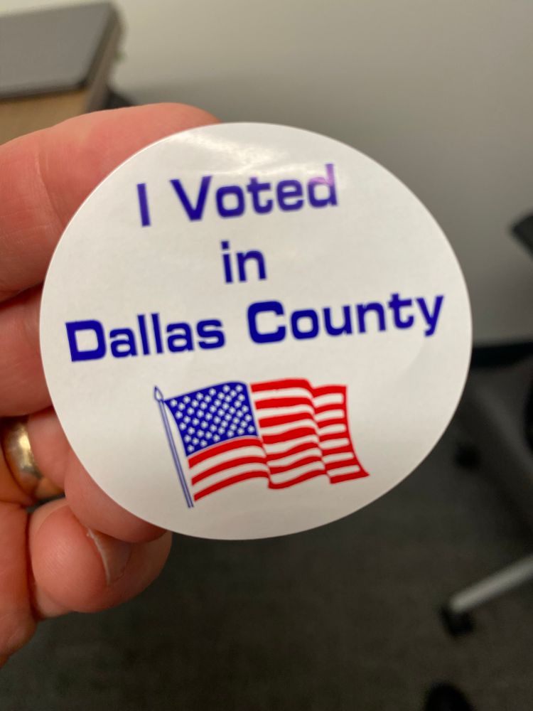 A round white sticker that says “I voted in Dallas County,” with a US flag underneath the words.