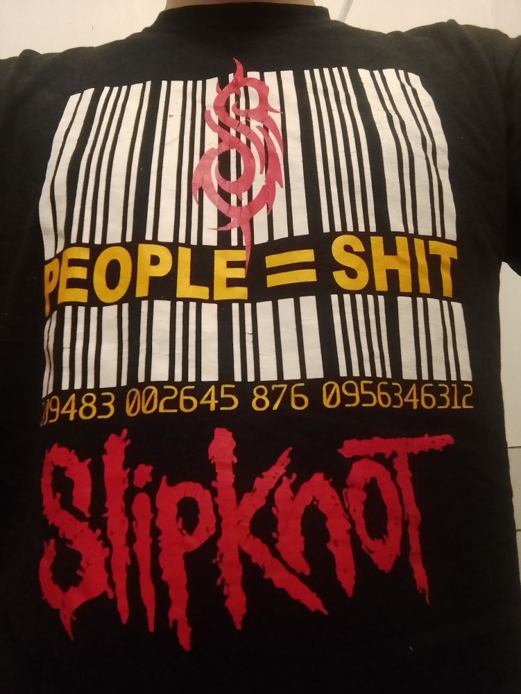 foto: schwarzes T-Shirt. darauf ein weißer barcode, unterbrochen von dem gelben schriftzug "people = shit". der barcode ist überlagert von einem stilisierten roten "s" dem logo der band slipknot, deren name in rot unter dem barcode steht