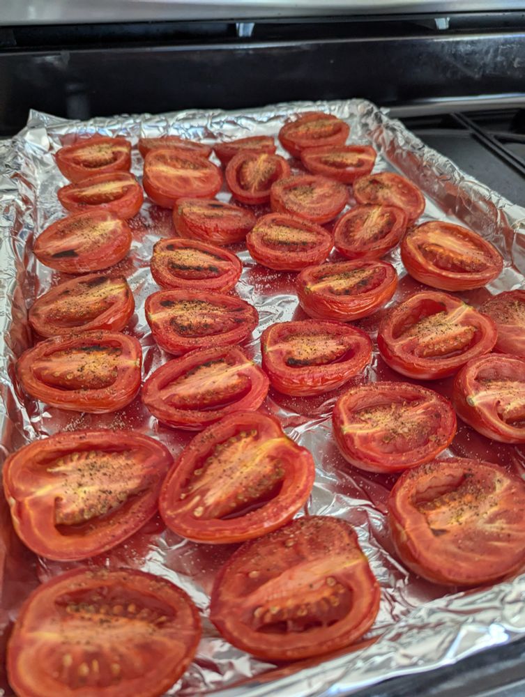A foil lined sheet pan filled with roasted roma tomatoes