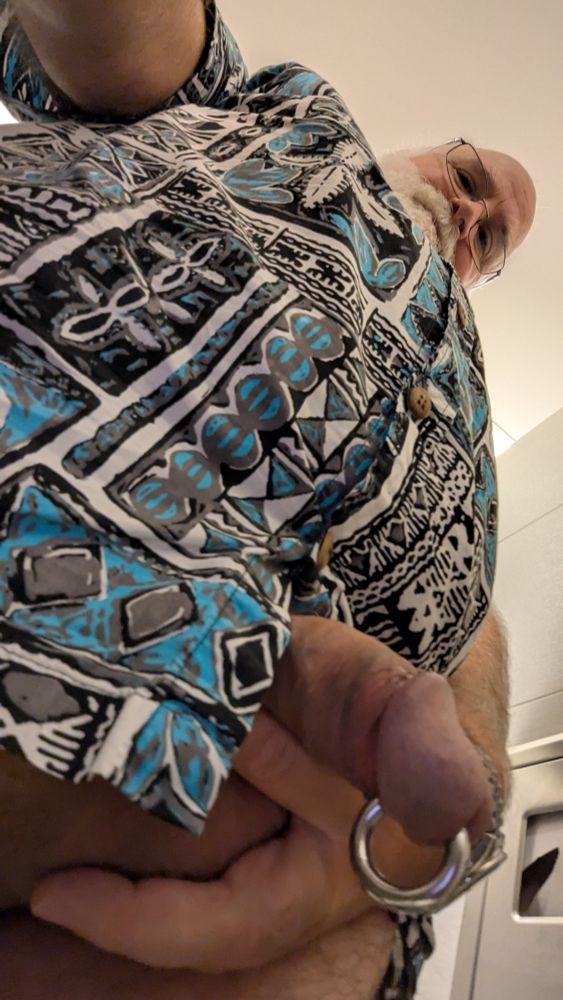 GupDaddy looking down as the viewer looks up from just under his plump, but not quite hard cock, a solid Prince Albert piercing looped through the tip weighing it down.