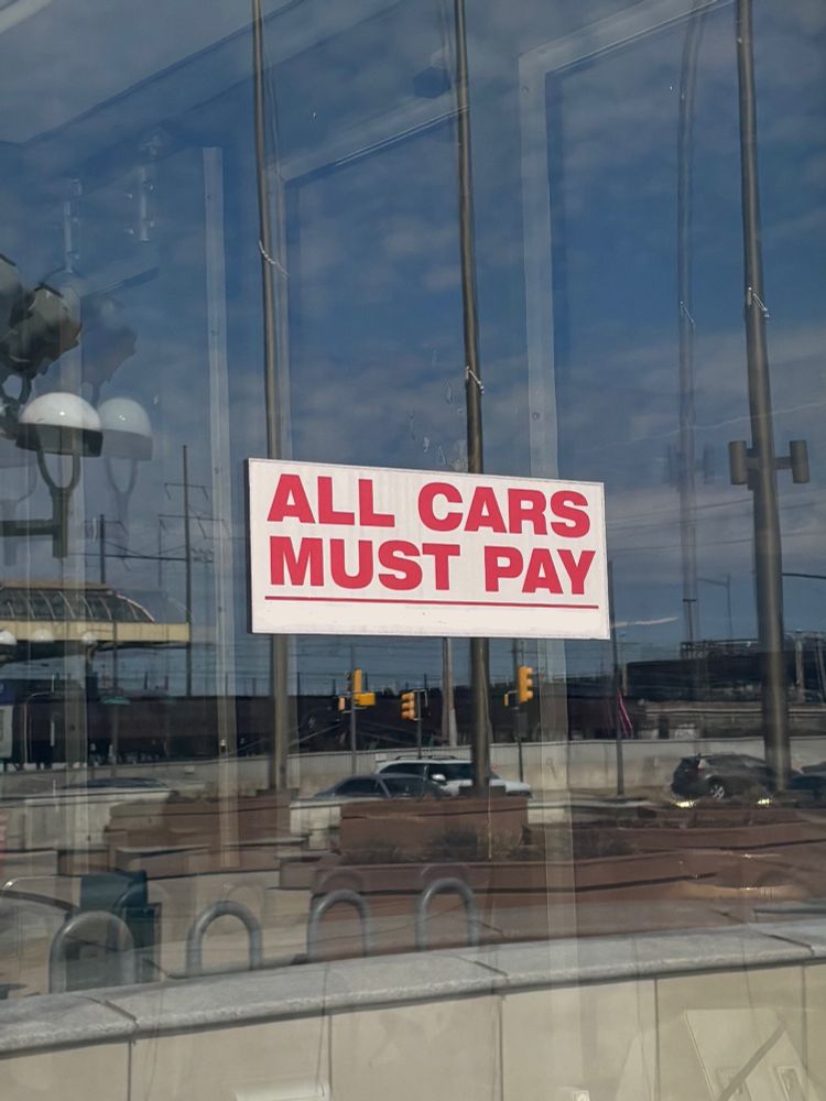 a sign on a window with the words “all cars must pay”