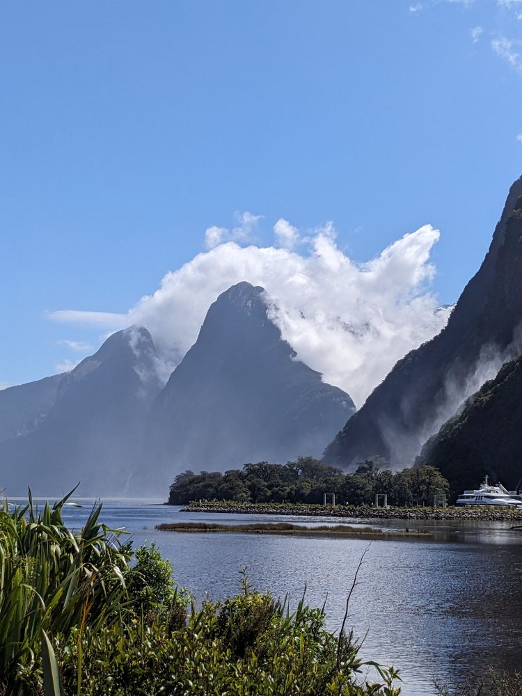 Clouds blowing off seaside mountains under an otherwise clear blue sky 